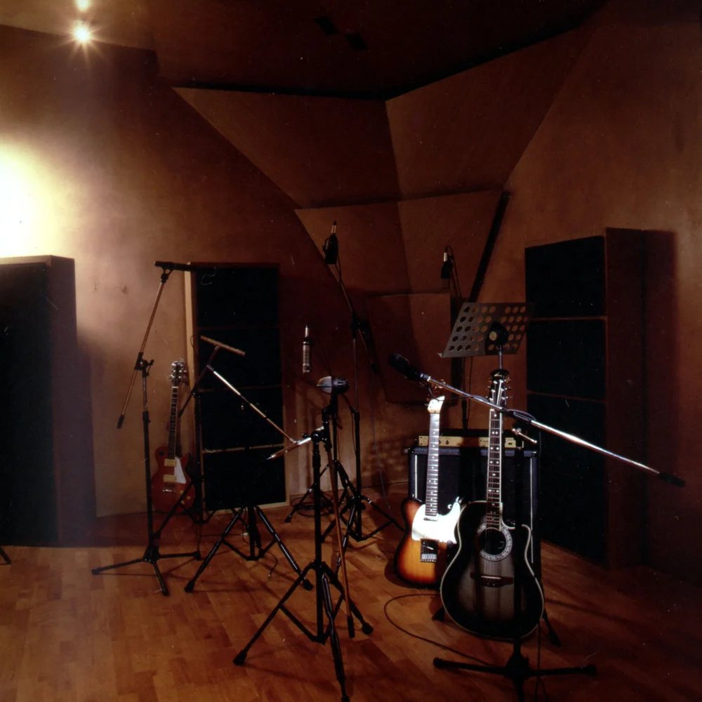 The live room, set up with guitars, microphone stands and acoustic panelling